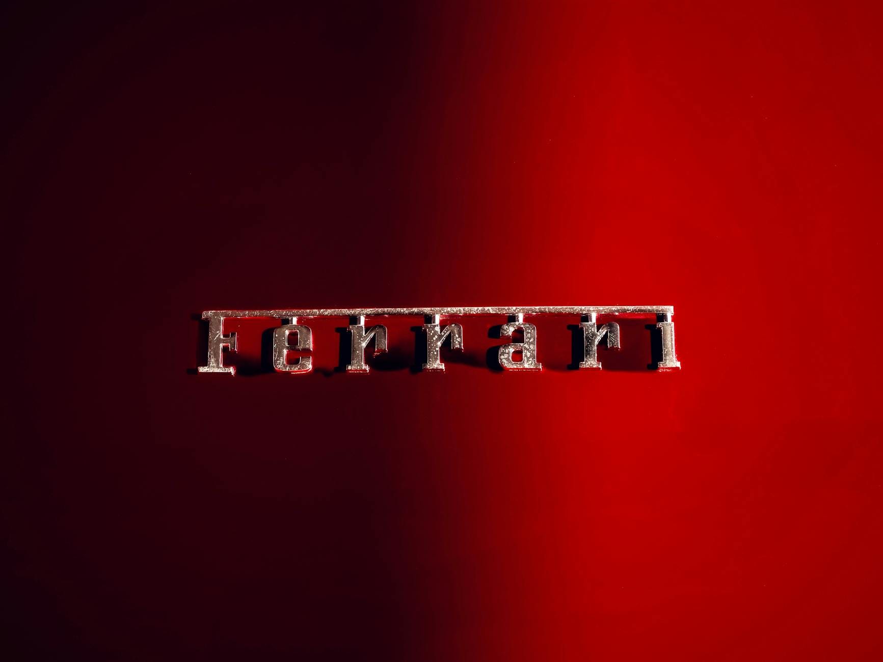 Zbliżenie na emblemat Ferrari na błyszczącym czerwonym nadwoziu