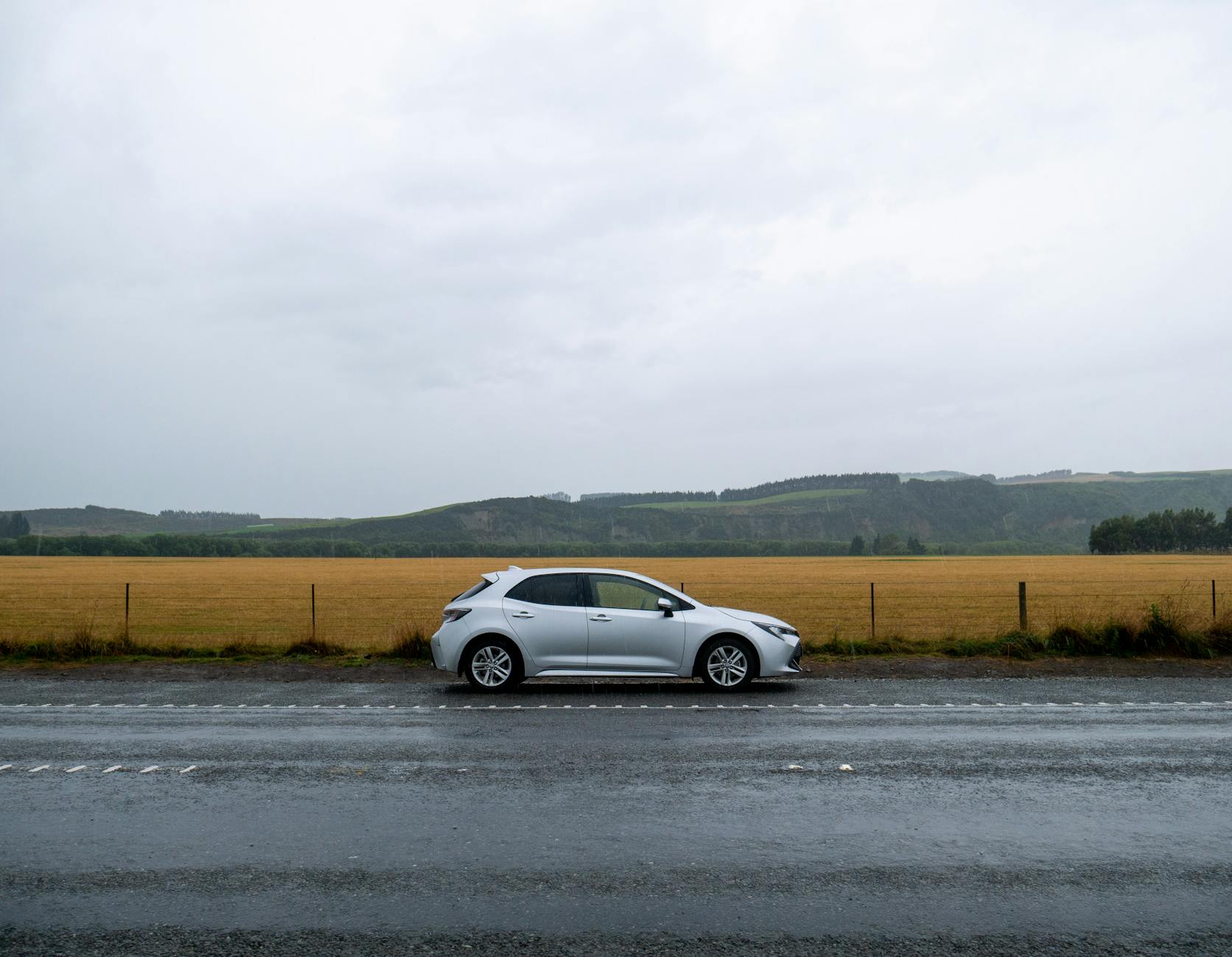 Srebrne Alfa Romeo 156 zaparkowane na mokrej drodze przy polu siana