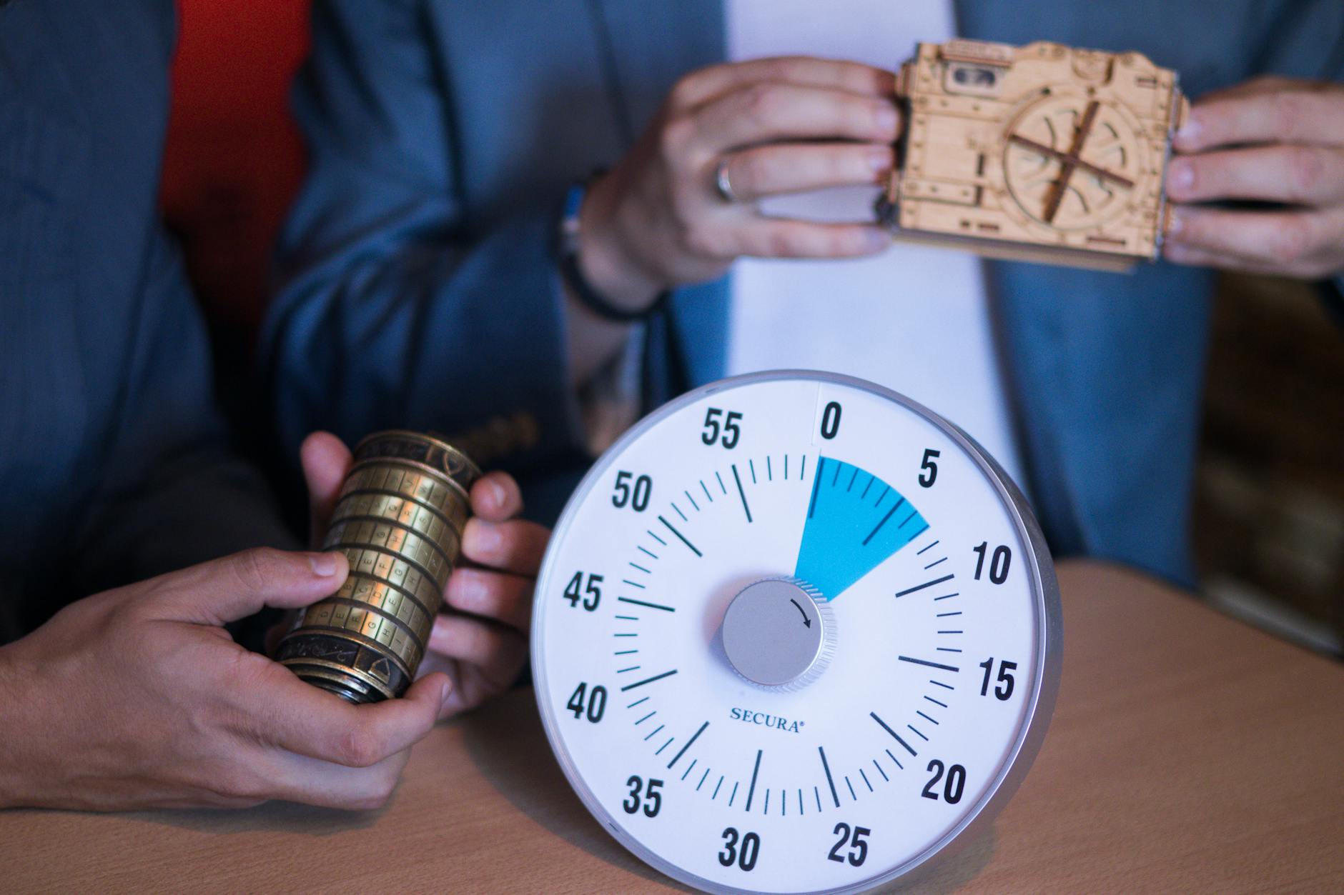 Dłonie dziecka trzymają kłódkę i timer podczas zabawy w escape room