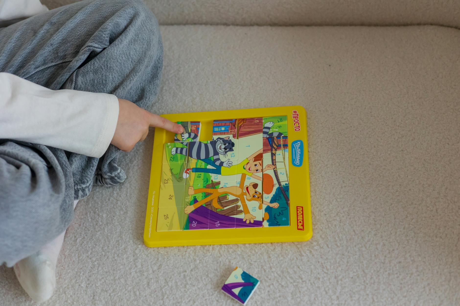 Dziecko na dywanie układa kolorową edukacyjną układankę