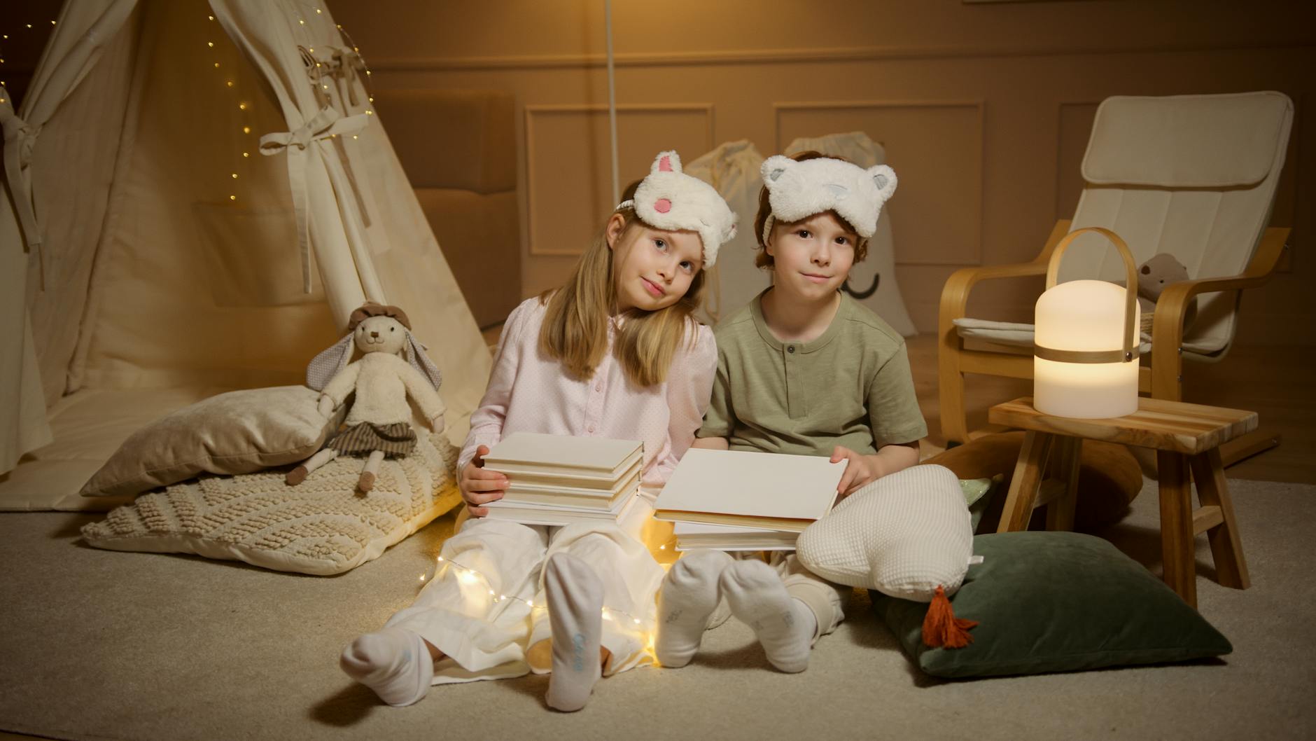 Dwoje dzieci w piżamach czyta książki w namiocie w pokoju