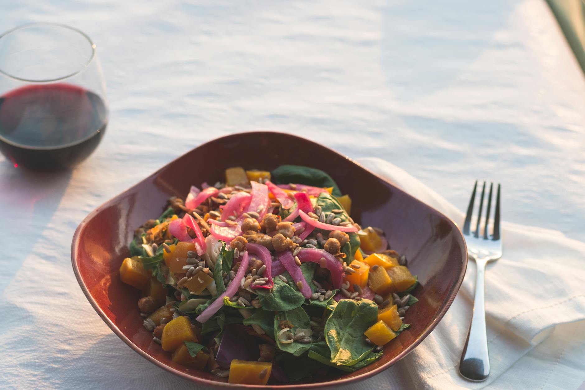 Sałatka warzywna i kieliszek czerwonego wina na słonecznym tarasie