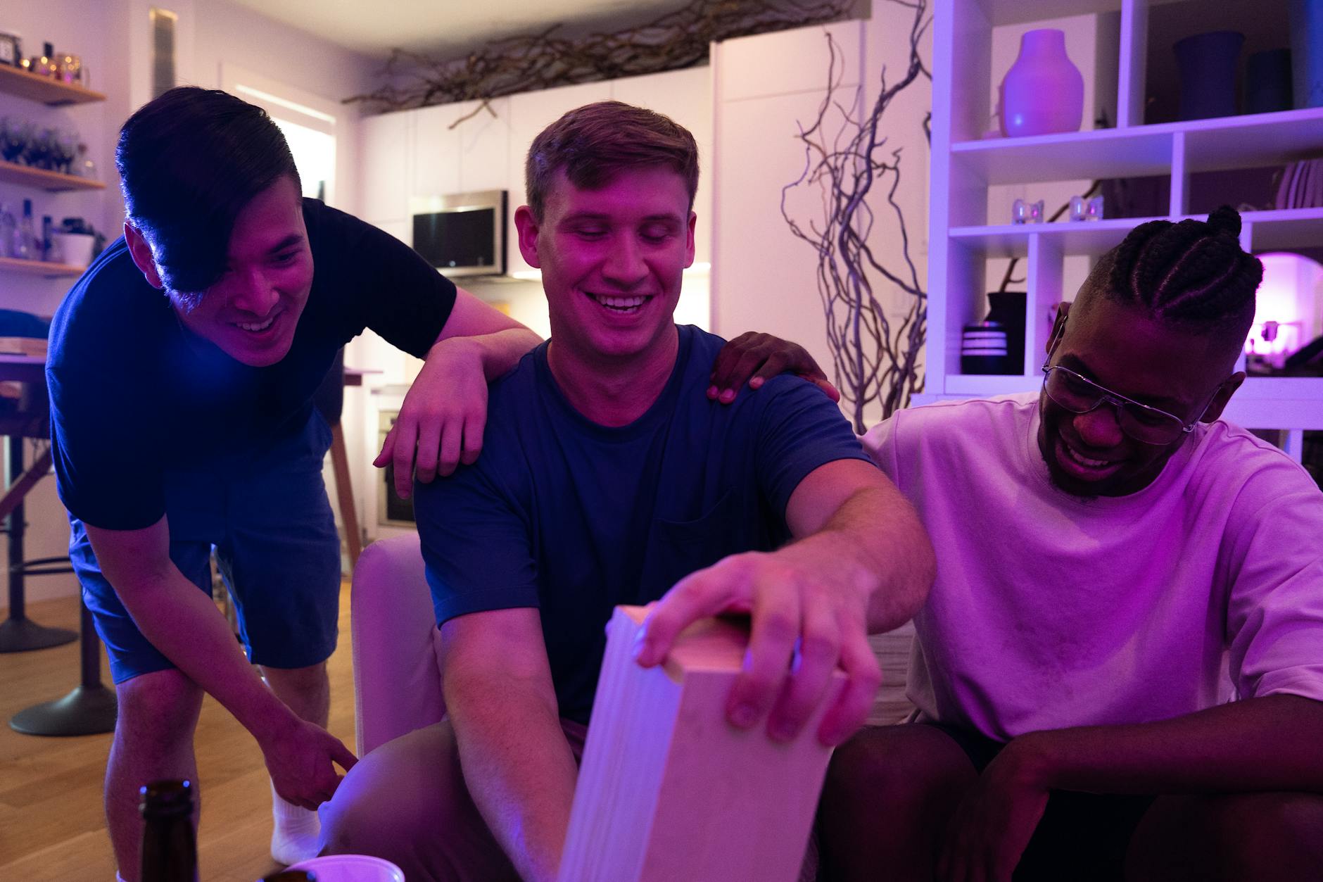 Trojka przyjaciół śmieje się przy wspólnej wieczornej grze w pokoju