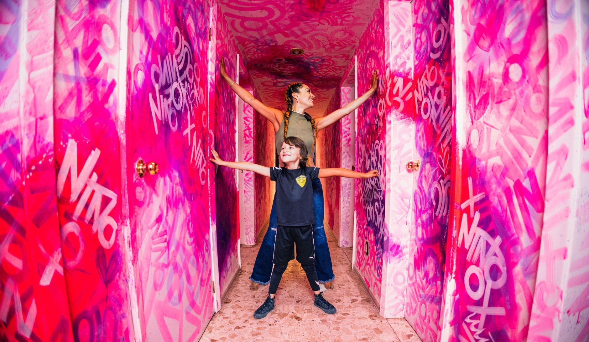 Mama z synem uśmiechają się w różowym korytarzu z graffiti